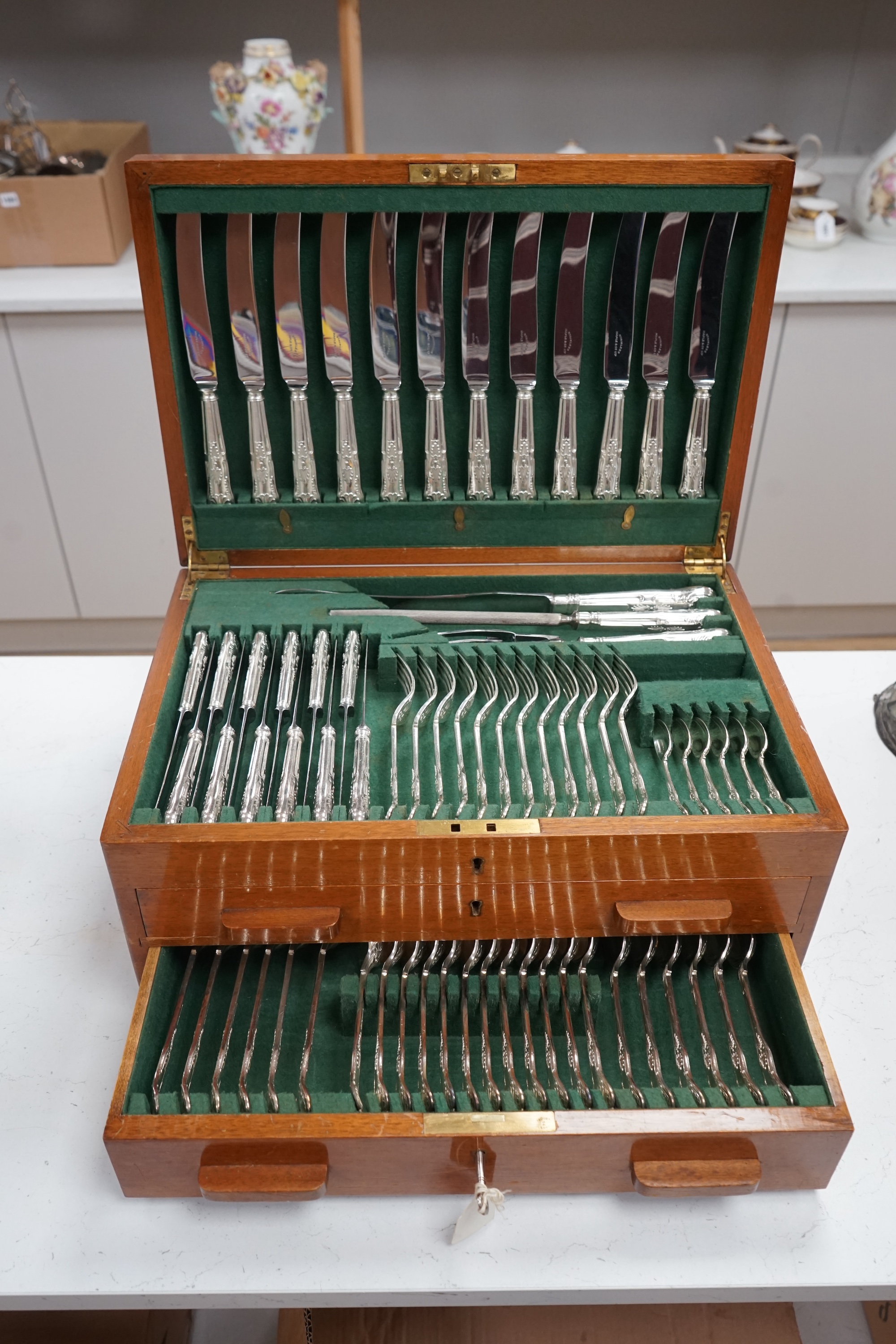 A mid 20th century canteen of Maple & Co silver plated King's pattern cutlery for twelve, comprising ninety six items, together with three odd pairs of plated sugar tongs, housed in a three drawer mahogany canteen with k